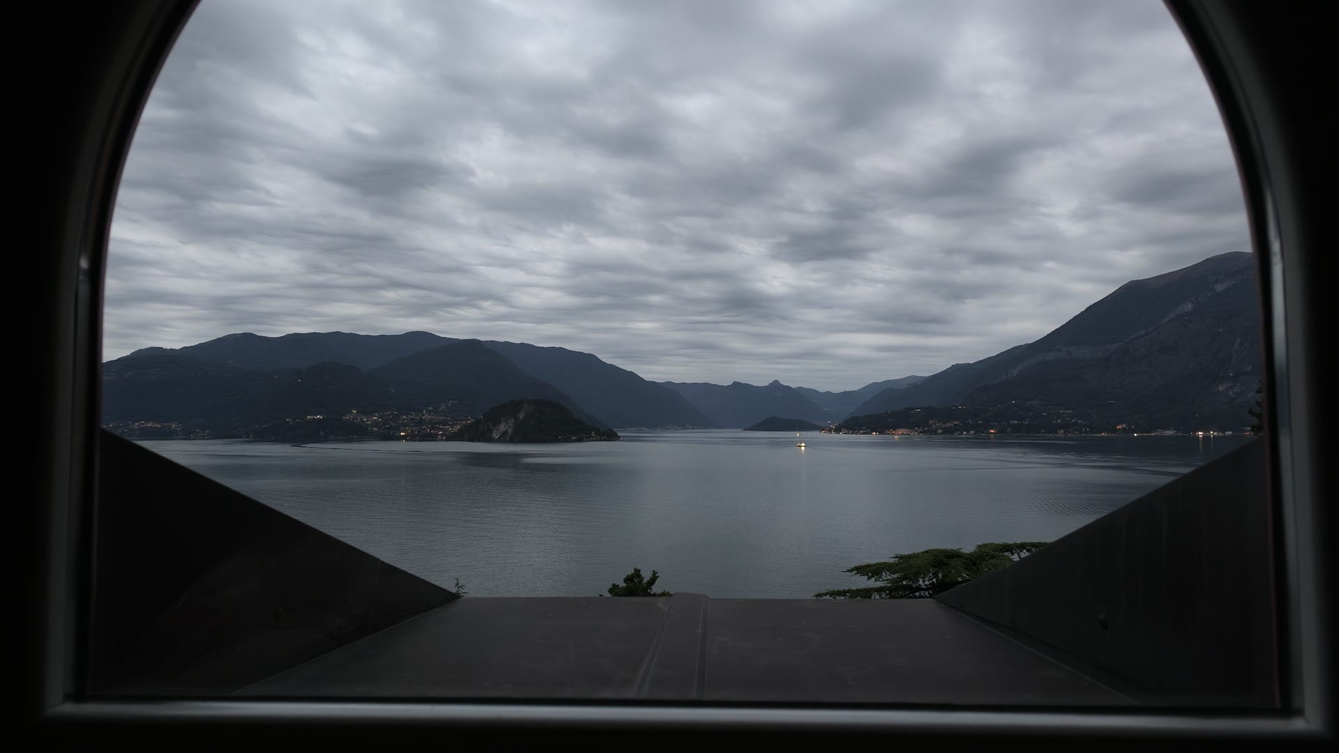 雲のある朝に丸窓から見たコモ湖